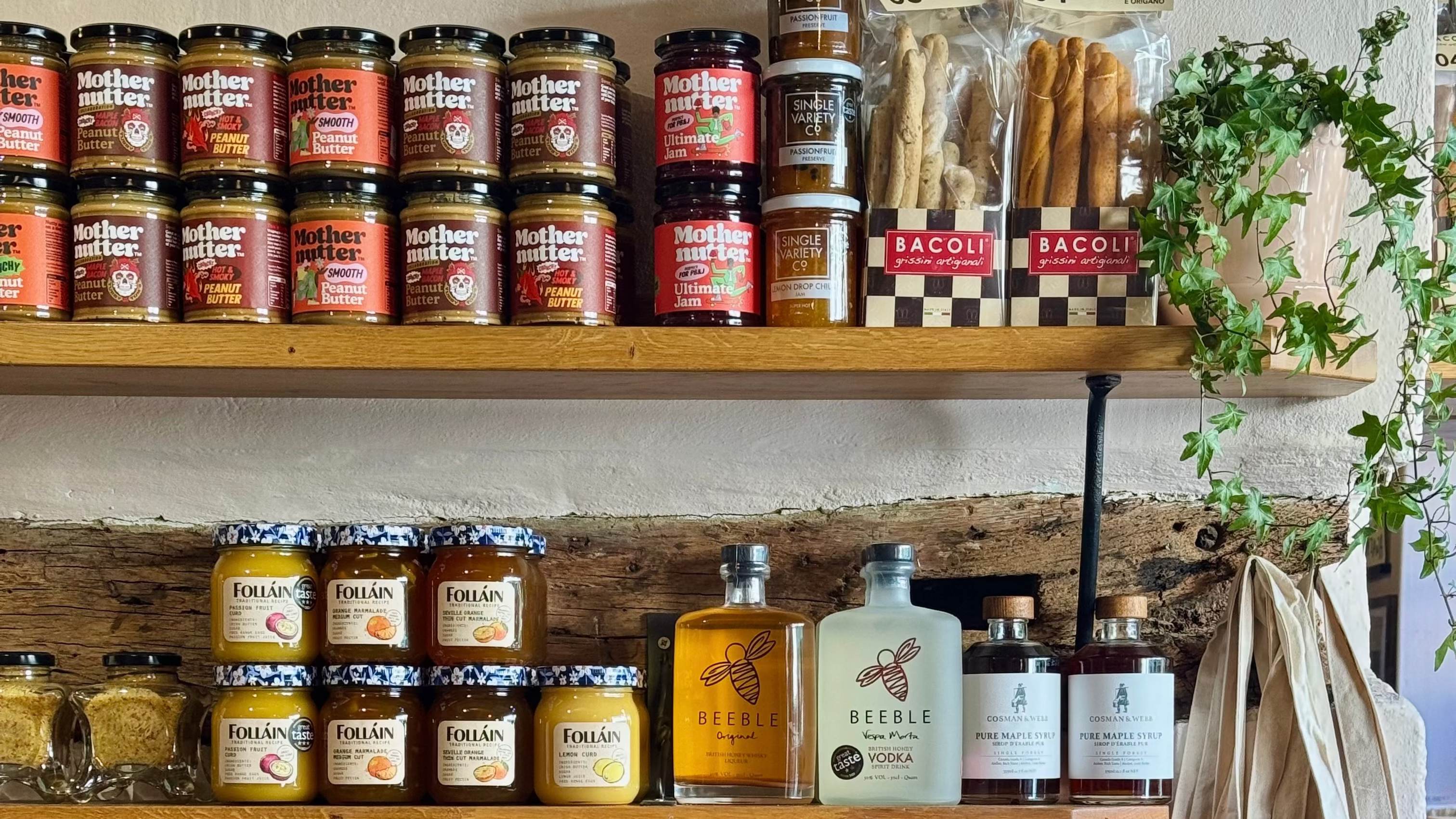 Shelf with various jars, bottles, and bags against a brick wall with a Perello bag in the foreground.